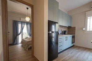 A modern kitchen with a black refrigerator, light blue cabinets, and a wooden countertop. - Blue Nest Apartment by RentalsPro - Dionisiou Beach (Dionisiou Beach)