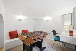 Ett rum med ett bordfotbollsspel, ett skrivbord, en stol och en lampa.