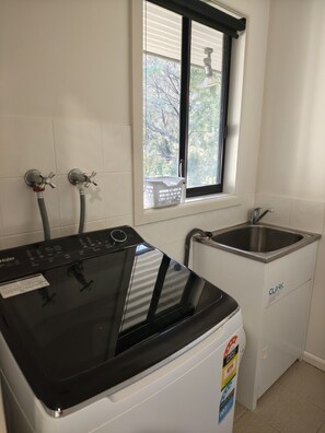 A compact laundry area with a front-loading washing machine and a built-in sink. - Kookaburra Lookout (Halls Gap)