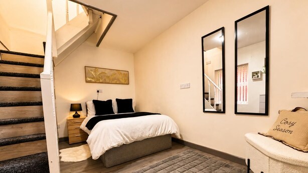 Quarto com cama, mesa de cabeceira, abajur e tapete.
