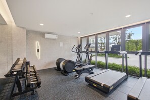 Un gimnasio con equipo de ejercicio, una cinta de correr y una ventana con vistas a zonas verdes.