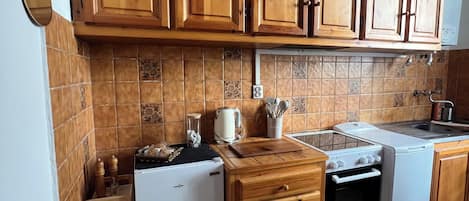 A kitchen with wooden cabinets, a white refrigerator, a stove, and a sink.