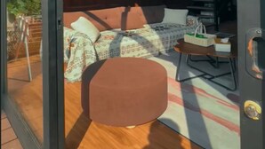 Un intérieur moderne avec un ensemble de canapés, une table basse et une porte vitrée donnant sur l’extérieur.