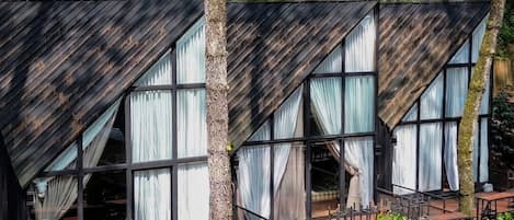 A cabin with a sloped roof, large windows, and a wooden deck.