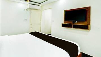 A hotel room with a bed, a television mounted on the wall, and a door.