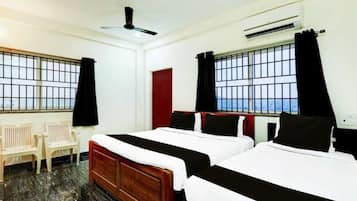 A hotel room with two beds, a ceiling fan, an air conditioning unit, and a view through the window.