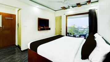 Une chambre d’hôtel avec un lit, une télévision, une fenêtre donnant sur un paysage agréable et une porte.