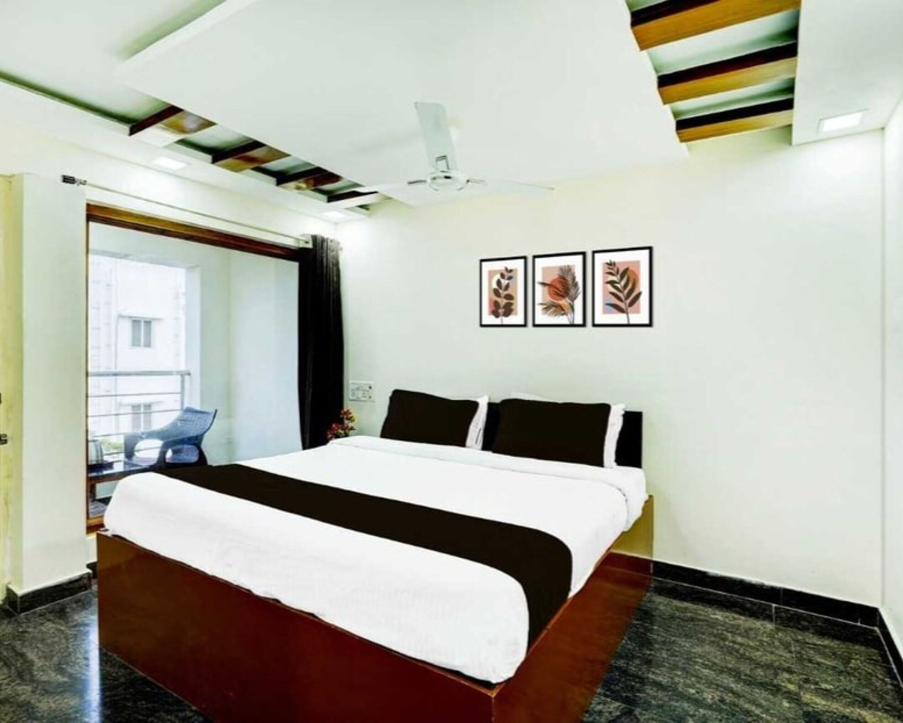 A modern hotel room with a large bed, a ceiling fan, and framed artwork on the wall.