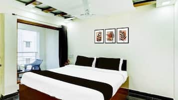 Une chambre d’hôtel moderne avec un grand lit, un ventilateur de plafond et des œuvres d’art encadrées accrochées au mur.
