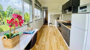 Une cuisine moderne avec vue sur l’extérieur, un coin repas avec un banc et un comptoir de cuisine équipé d’appareils électroménagers.