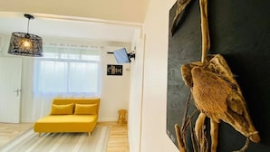 Un salon moderne avec un canapé jaune, un luminaire suspendu et un grand tableau abstrait.