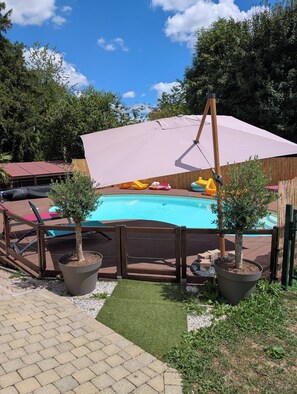Ein Garten mit Swimmingpool, Holzterrasse und Kübelpflanzen.