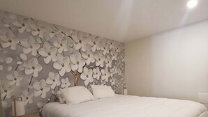 Ein Schlafzimmer mit einem Bett, einem Nachttisch und einer Wand mit floralem Muster.
