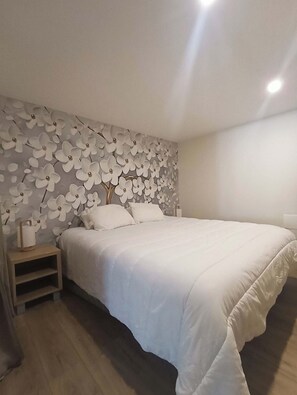 Ein Schlafzimmer mit einem Bett, einem Nachttisch und einer Wand mit floralem Muster.