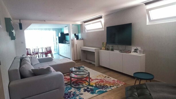 Ein modernes Wohnzimmer mit einer Couch, einem Couchtisch und einem Fernseher.