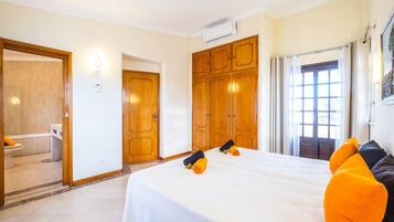 Een hotelkamer met een groot bed, een houten garderobe en een zichtbare badkamer door een geopende deur.