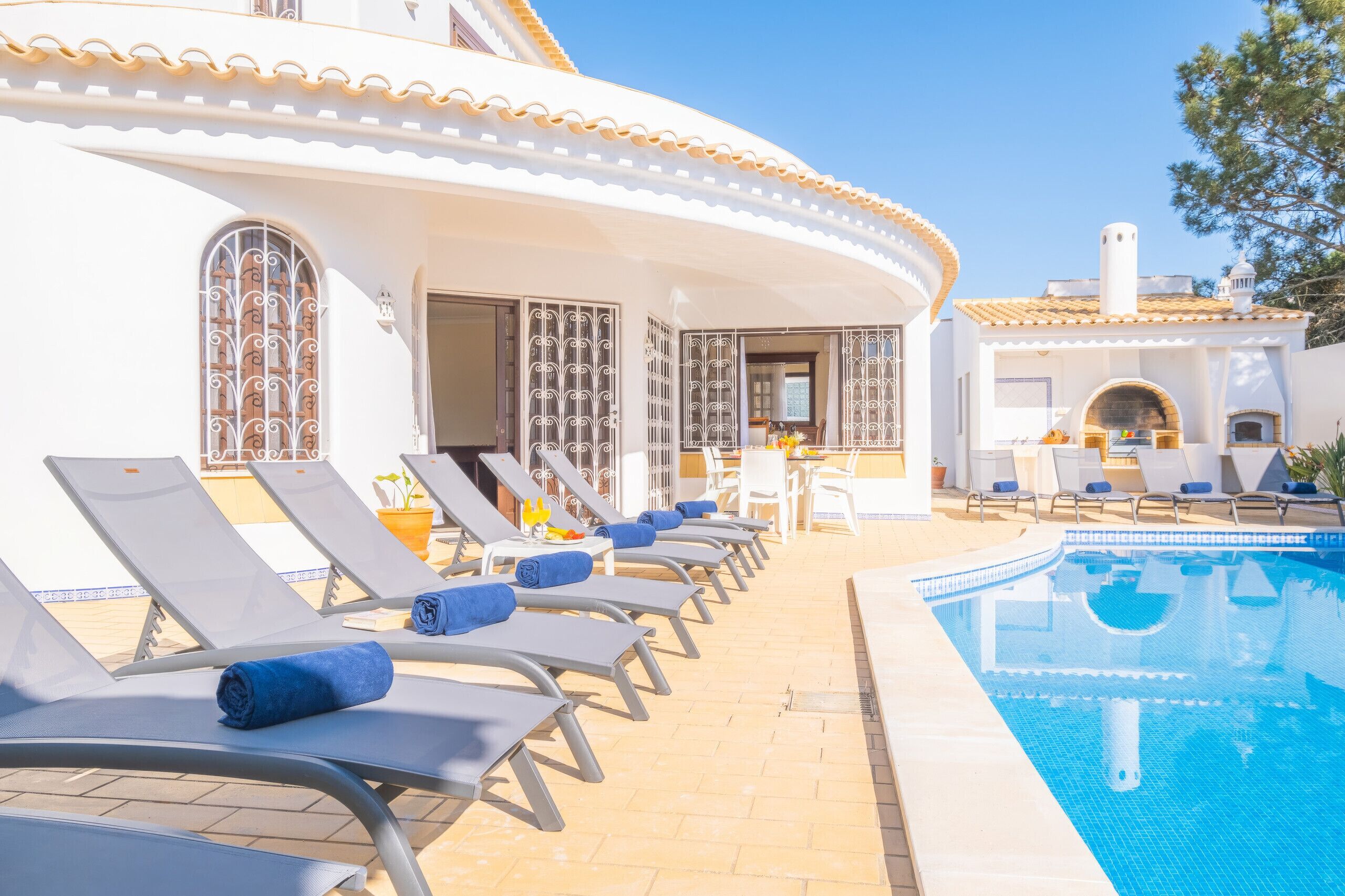 A poolside area with sun loungers and a clear blue pool.
