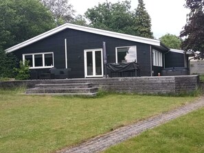 A two-story house with a covered patio area and a set of outdoor furniture. - 5 Star Holiday Home in Olsted (Olsted)