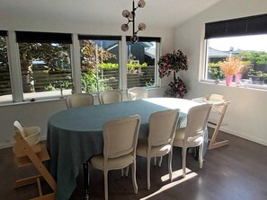 A dining area with a round table, six chairs, and a view of the outdoors through large windows. - 5 Star Holiday Home in Olsted (Olsted)