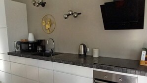 Eine moderne Küche mit Einbauofen, Spüle und einem flachbildfernseher an der Wand.