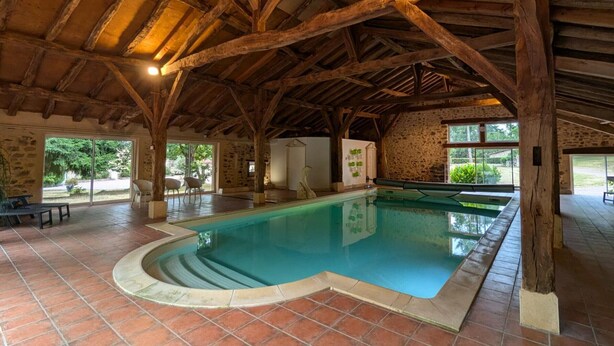 An indoor swimming pool with a stone wall and wooden beams. - Independent house in nature - 4 guests (Esse)