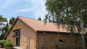 A stone building with a tiled roof, a gravel driveway, and a large tree to the right. - Independent house in nature - 4 guests (Esse)