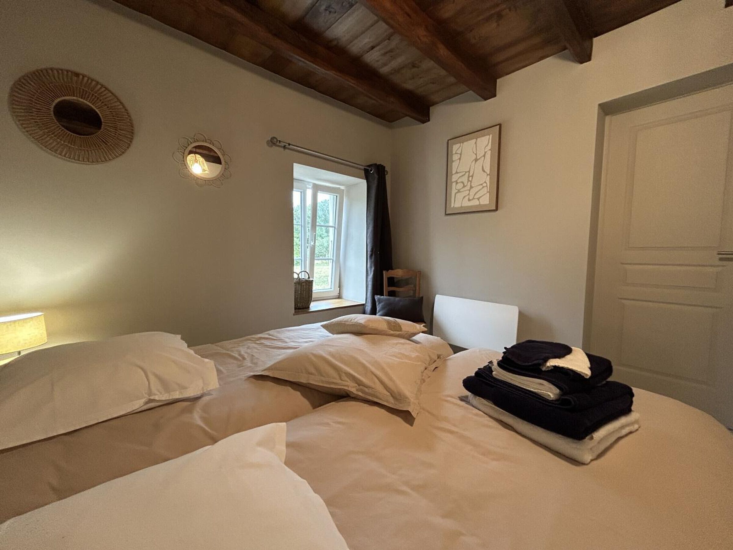 Une chambre avec deux lits, une fenêtre, une porte et un luminaire fixé au mur.