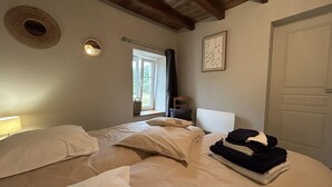 A bedroom with two beds, a window, a door, and a wall-mounted light fixture. - Independent house in nature - 4 guests (Esse)