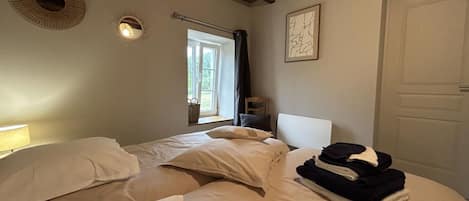 Un dormitorio con dos camas, una ventana, una puerta y una lámpara fijada a la pared.