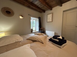 Ein Schlafzimmer mit zwei Betten, einem Fenster, einer Tür und einer Wandleuchte.