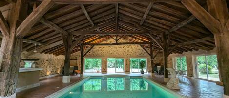 Una piscina interior con pared de piedra y vigas de madera.