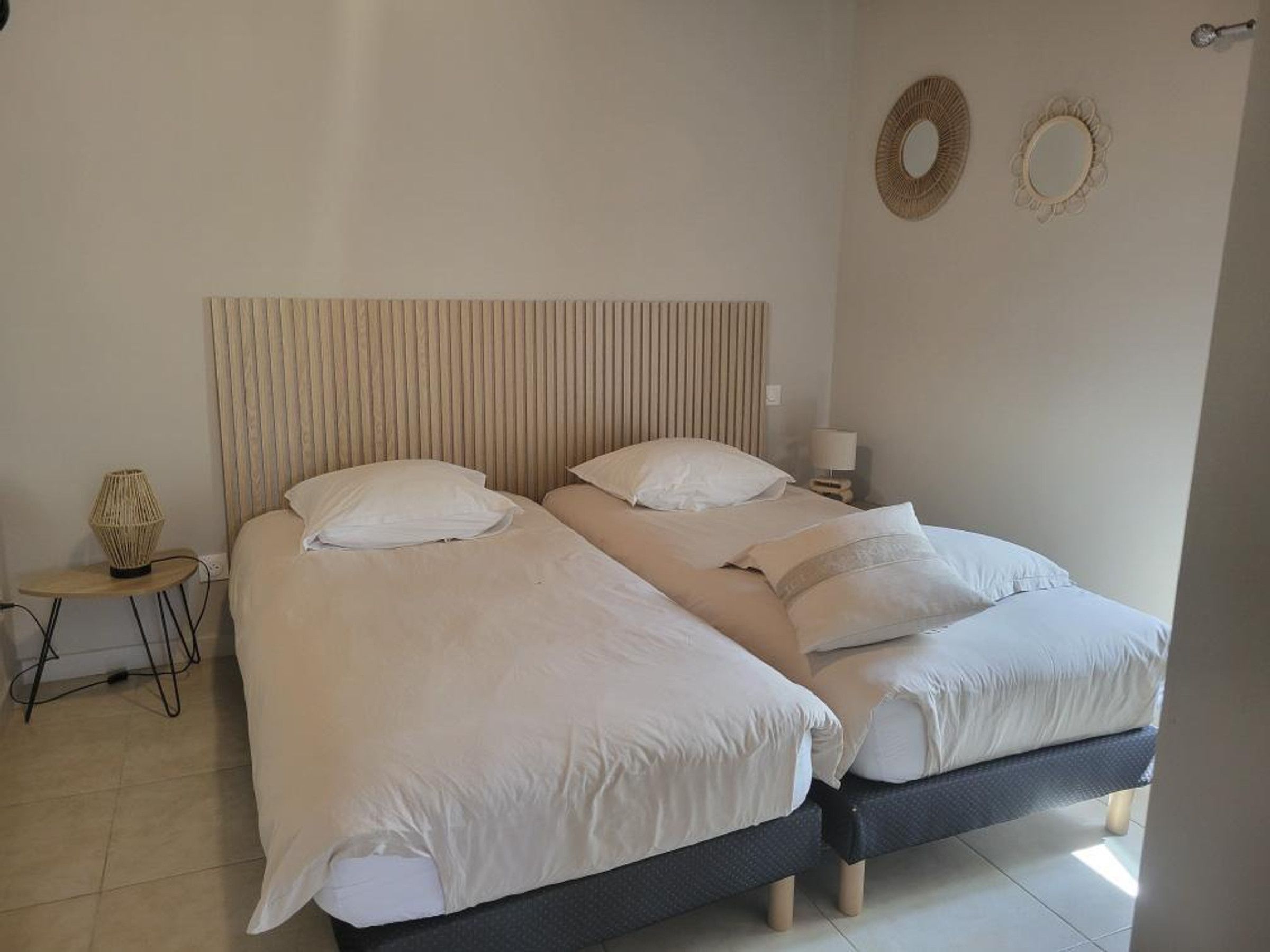 A double bed with a wooden headboard, two bedside tables, and a small round table with a lamp.