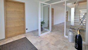Un intérieur moderne avec une porte en bois, une porte vitrée donnant sur un escalier, et une bouteille de champagne posée sur le sol.