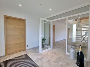 Ein modernes Interieur mit einer Holztür, einer Glastür zum Treppenhaus und einer Champagnerflasche auf dem Boden.