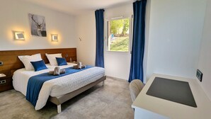 Une chambre à coucher avec un lit, des tables de chevet, un bureau et une fenêtre avec des rideaux.