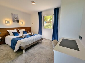 Ein Schlafzimmer mit einem Bett, Nachttischen, einem Schreibtisch und einem Fenster mit Vorhängen.