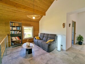 Ein modernes Wohnzimmer mit einem grauen Sofa, einem runden Couchtisch und einem Bücherregal.