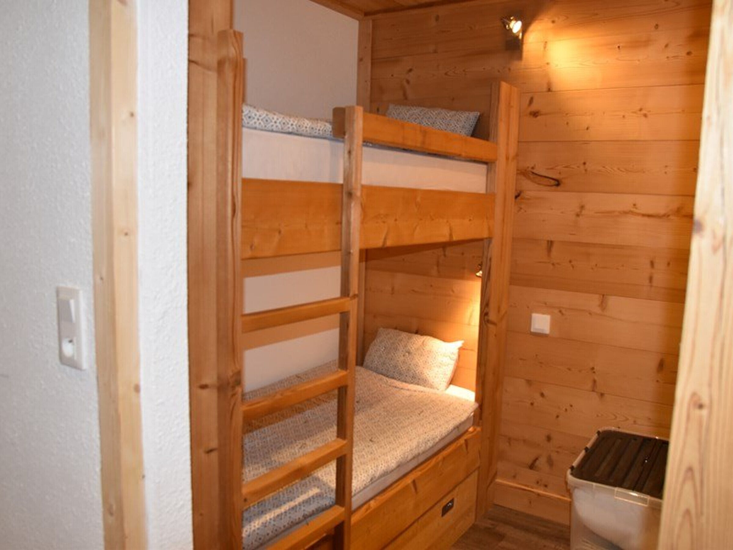 Une petite pièce de style cabane en bois, avec des lits superposés et un lit simple.