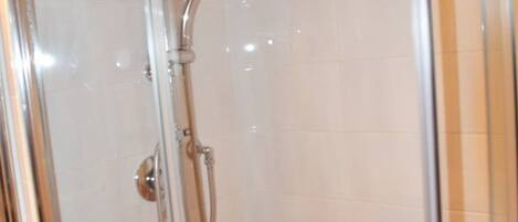 A glass-enclosed shower area with a chrome showerhead and a red bathtub.