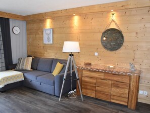A cozy room with a grey sofa, a lamp, a wooden cabinet, and a wall clock. - Apartment with balcony and mountain view (Montgenèvre)