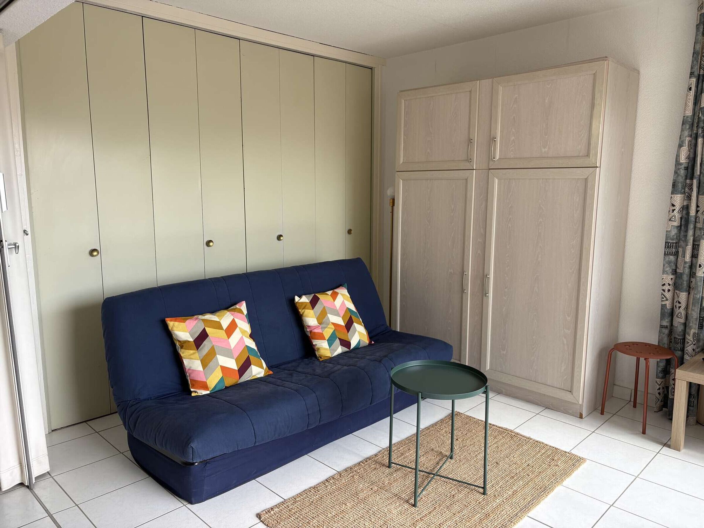 Une pièce avec un canapé bleu, une petite table ronde et un tapis tissé.