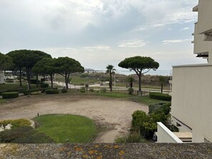 Ein Wohngebiet mit einem gepflasterten Innenhof, Bäumen und Blick auf das Meer.