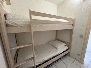 Un lit superposé avec une literie blanche et une structure en bois.
