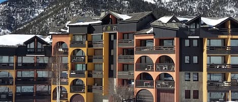 A multi-story hotel with balconies and a ski resort backdrop.