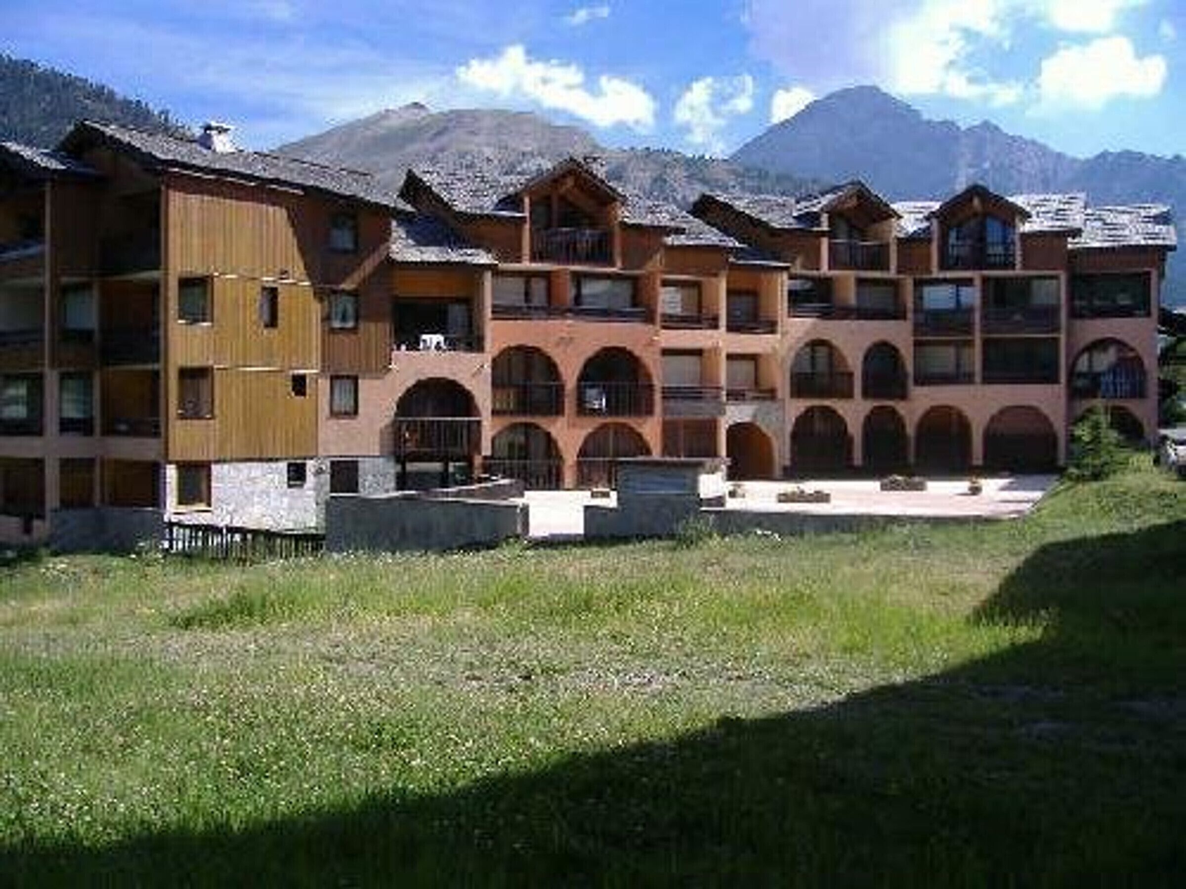 Un hotel de varios pisos con un patio central, rodeado de montañas.