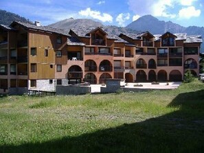 A multi-story hotel with a central courtyard, surrounded by mountains. - Cozy apartment, balcony with slopes view - 4 guests (Montgenèvre)