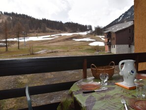 A table set for two with a view of a snowy landscape and a mountain in the background. - Cozy apartment, balcony with slopes view - 4 guests (Montgenèvre)