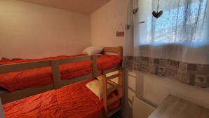 A dormitory room with bunk beds, a small desk, and a window with a curtain. - Cozy apartment, balcony with slopes view - 4 guests (Montgenèvre)