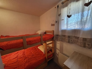 A dormitory room with bunk beds, a small desk, and a window with a curtain. - Cozy apartment, balcony with slopes view - 4 guests (Montgenèvre)
