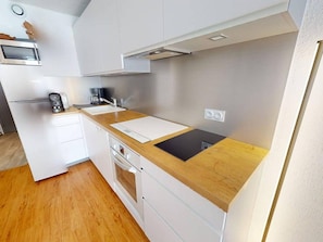 A compact kitchen with white cabinets, a wooden countertop, a built-in oven, and a microwave. - Ski-in/ski-out apartment, exceptional view - 6 guests (Les Arcs)